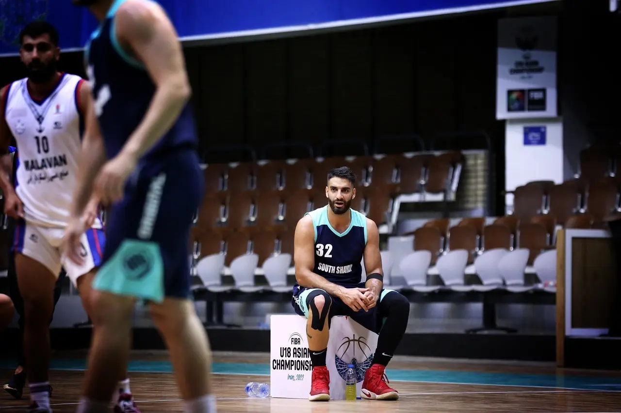 Basketballspiller siddende i tom hal